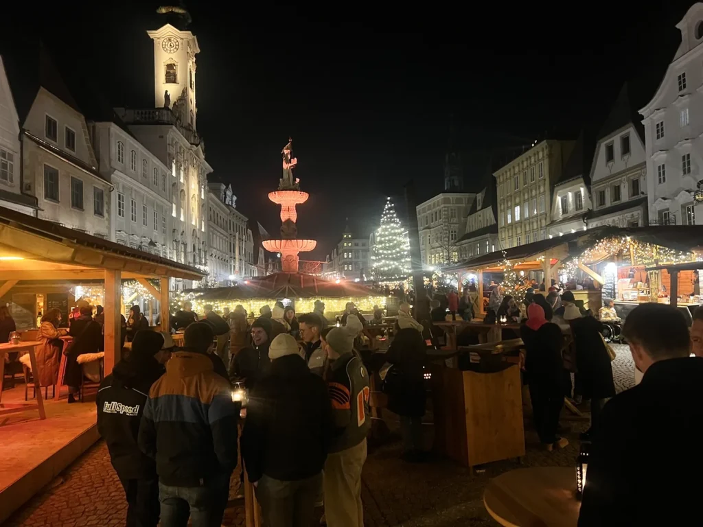 Abendstimmung im vollen Adventdorf mit Rathaus und Brunnen
